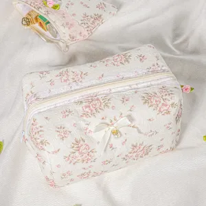 Detailed view of quilted floral cosmetic bag with lace trim, bow and pearl charm for daily makeup.