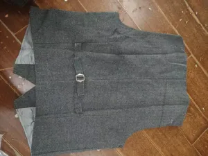 Detail view of mens grey herringbone suit vest back design with adjustable buckle strap