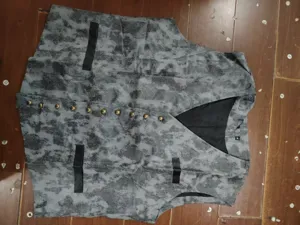 Detailed view of men's V-neck single-breasted waistcoat with marbled pattern and brass buttons.