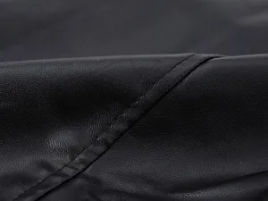 Primer plano de tela de cuero sintético negro con textura fina y costuras limpias.
