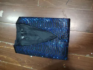 Detailed shot of men's black sequin vest collar and V-neck design, garment interior label.