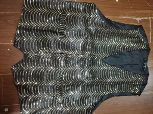 Men's black sequin vest detail showcasing the sparkling wave pattern design and button closure.