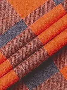 Flannel fabric detail texture shot showing classic orange and dark grey plaid check pattern.