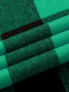 Detailed close-up view of soft green and black flannel plaid fabric shirt texture.