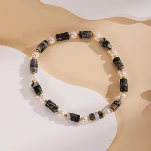 Primo piano dettaglio del bracciale di perle vintage con cilindri in pietra nera.