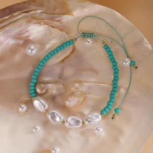 Gros plan détaillé de bracelet de perles turquoise et perles baroques avec cordon vert.