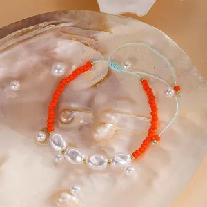 Gros plan de bracelet artisanal en perles de rocailles colorées et perles baroques réglable.