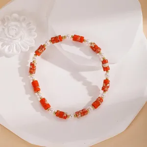 Primo piano dettagliato del braccialetto di perle vintage con perline cilindriche rosse.