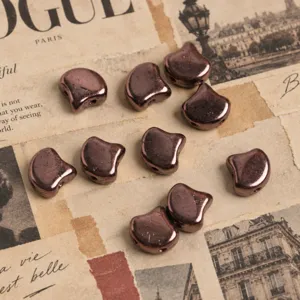 Close-up of metallic copper double-hole ginkgo beads, perfect for DIY jewelry crafting details.