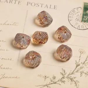 Primo piano di perline di vetro ceco vintage sfaccettate con spina di pesce e riflessi iridescenti.