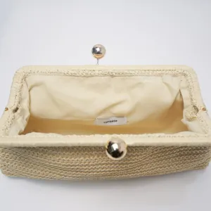 Detailaufnahme des gewebten Stroh-Clutch-Innenraums mit Metallverschluss und Futter.