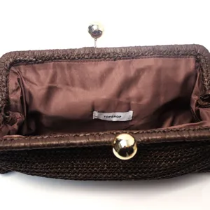 Braune gewebte Stroh-Clutch Tasche mit Metallkugelschluss und Innenfutter Detail.