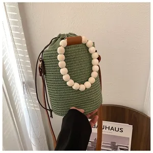Green woven straw bucket bag with wooden bead handle and brown shoulder strap for women beach.