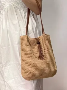 Handmade crochet straw tote bag with brown leather strap and tassel for women beach vacation.