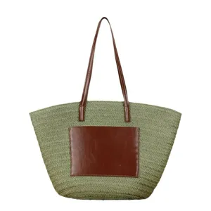 Green woven straw beach tote bag with brown leather handles and front pocket for summer.