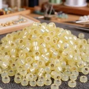 Vista di dettaglio di rocaille gialle foderate d'argento da 2mm per gioielli fai da te.