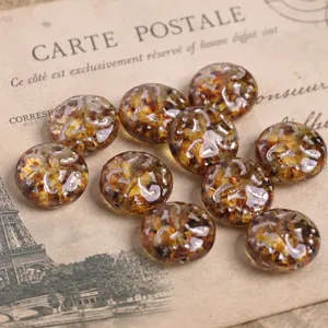 Dettaglio di perle di vetro ceche, forma piatta color ambra con dettagli in argento.