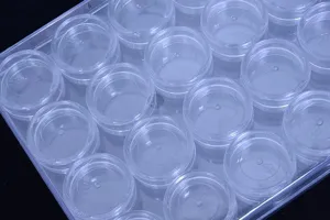 Détail de boîte de rangement en plastique transparent, petits pots ronds clairs pour perles.