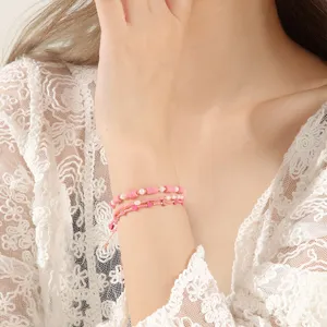 Close-up detail of handmade pink beaded layered bracelet with heart charms and sweet pearls.