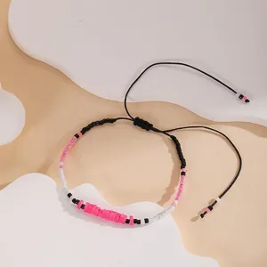 Close-up of a handmade woven bead bracelet with black, white, and pink colorful beads.