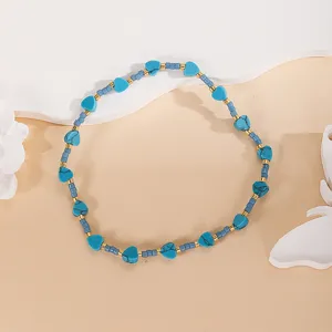 Closeup of blue turquoise heart beads and gold metal spacers on elegant neutral display background