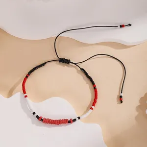 Close-up detail of a handmade beaded bracelet featuring red, black, and white seed beads.