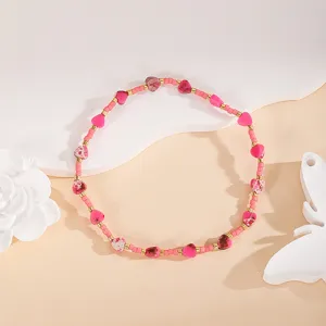 Close-up detail of handmade pink heart beaded bracelet with gold metallic spacer beads.