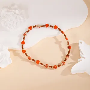 Handmade heart beaded bracelet detail, featuring red stone beads and metallic spacer accents.
