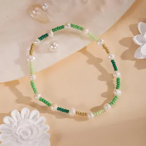Primo piano di un delicato braccialetto di perle con perline verdi e dorate colorate.
