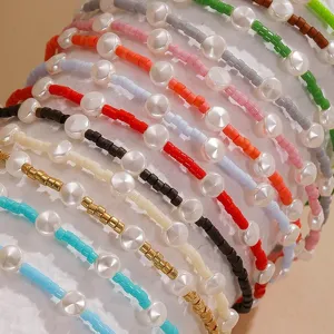 Close-up of colorful seed bead bracelets featuring white pearl disk accents in varied tones.