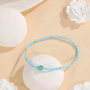 Close-up of minimalist seed bead bracelet with turquoise centerpiece and gold spacers, detail view.