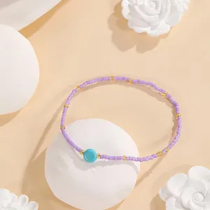 Purple seed bead bracelet detail with turquoise stone and gold spacers. Elegant boho chic jewelry.