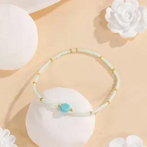 Close-up detail of minimal seed bead bracelet with turquoise stone and delicate gold spacers.