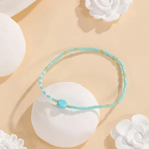 Minimalist turquoise seed bead bracelet with gold accents and central stone for daily wear.