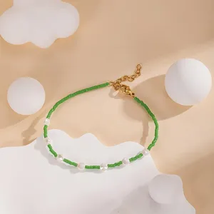Chic handmade green seed beads and white pearl bracelet with adjustable gold chain link detail.