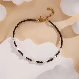 Minimalist handmade dark seed bead and white pearl bracelet with adjustable gold chain for women.