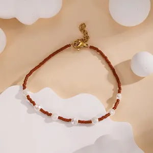 Close-up detail shot of brown seed beads and white pearls bracelet with a gold metal clasp.