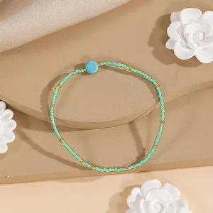 Close-up detail of minimalist ethnic woven seed bead bracelet with turquoise stone accent.