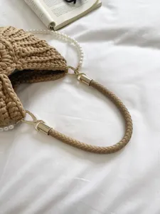 Gros plan détaillé d'un sac à main tissé avec poignée en cuir et chaîne de perles.