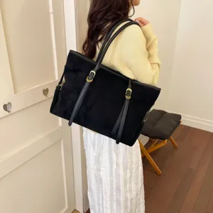 Vista detallada del bolso tote de ante negro que muestra gran capacidad y asas dobles elegantes.