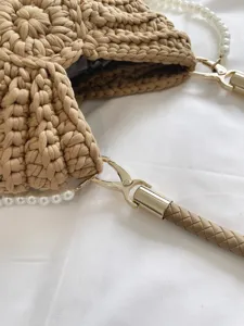 Détail de sac à main tissé avec texture crochet exquise, sangle de perles élégante et quincaillerie.