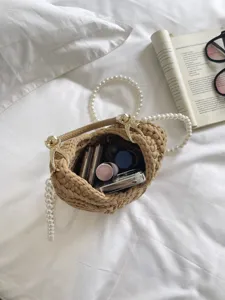Détail de sac à main tissé beige avec bandoulière de perles et détails dorés dans un cadre chaleureux.