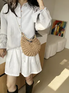 Vue détaillée du sac bandoulière en paille tissée avec chaîne en perles élégante et design.