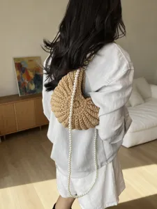Gros-plan détaillé d'un sac à bandoulière tissé tendance avec longue chaîne de perles.