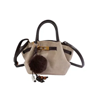 Detailed view of the vintage faux suede shoulder bag with chic hardware and plush pompom.