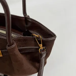 Detailed shot of dark brown suede shoulder bag, showing hardware and texture for daily wear.