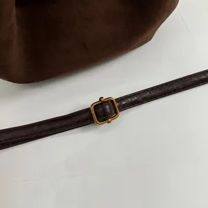 Detail shot of retro brown suede shoulder bag strap with metallic adjustable buckle for women.