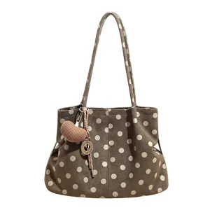 Vista detallada del bolso tote elegante de lunares con lindo colgante de punto de corazón.