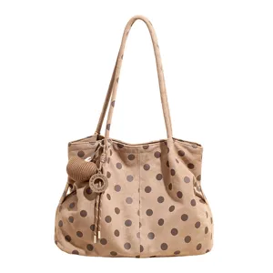 Vista detallada del elegante bolso tote de lunares con colgante fino y correas de hombro.
