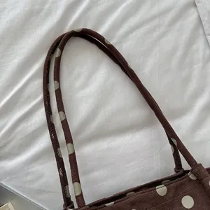 Primer plano detallado del asa del bolso tote de lunares marrones, textura de tela suave y peludo.